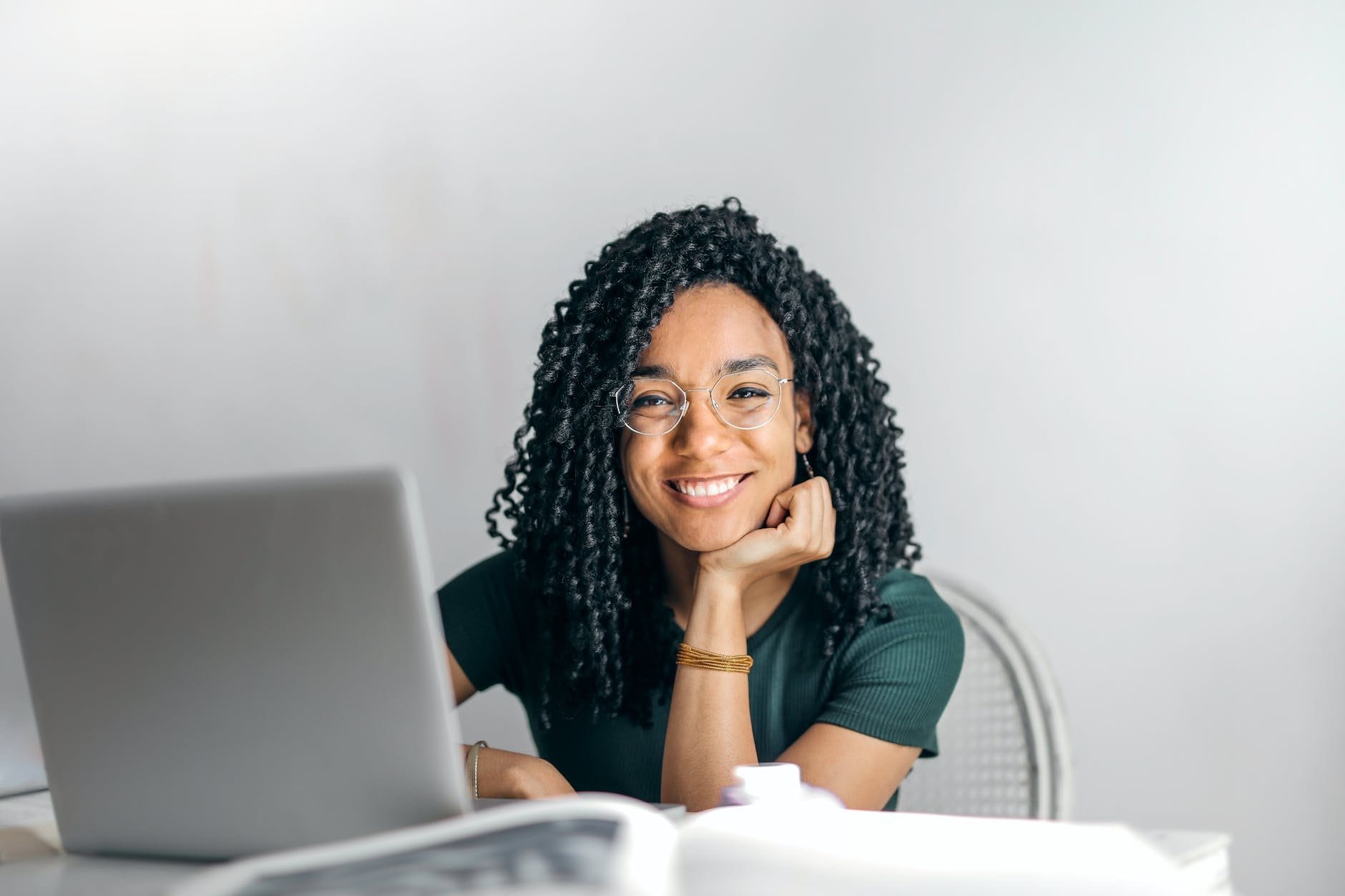 happy ethnic woman sitting at table with laptop thinking about product led growth for associations and nonprofits